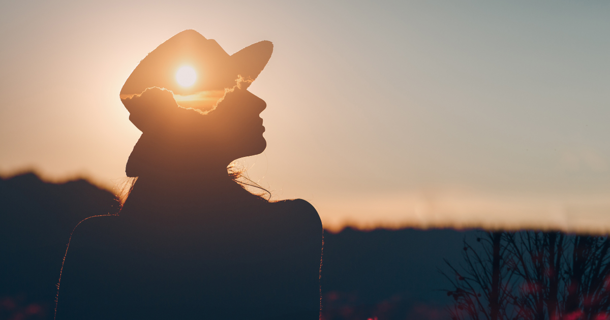 silhouette of a young woman with the sun shining inside her head to depict mental health
